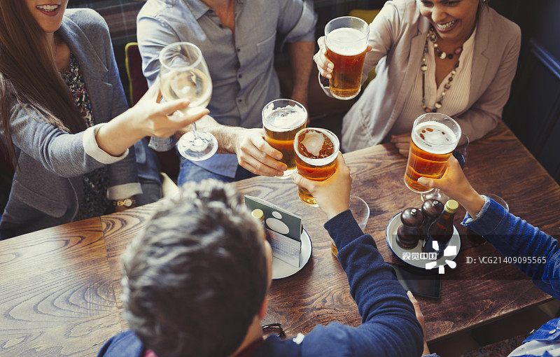 俯瞰朋友們在酒吧的餐桌上慶祝，舉杯互敬啤酒圖片素材