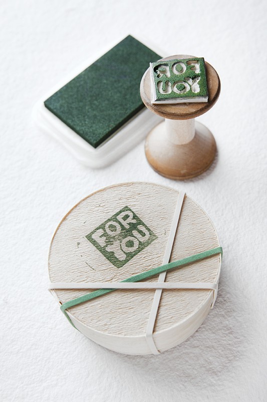 芯片木盒印刷motif讀“為你”;木柄上手工雕刻橡皮圖章，背景為印臺圖片素材