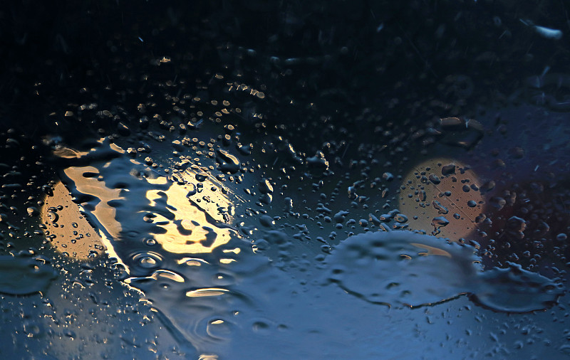 大雨時透過擋風玻璃看到的雨滴和交通燈圖片素材