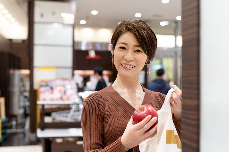 亞洲婦女在超市用可重復使用的棉花袋包裝蘋果圖片素材