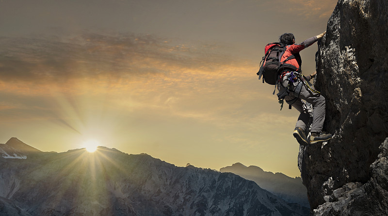 日落時分，一名登山者站在巖壁上圖片素材