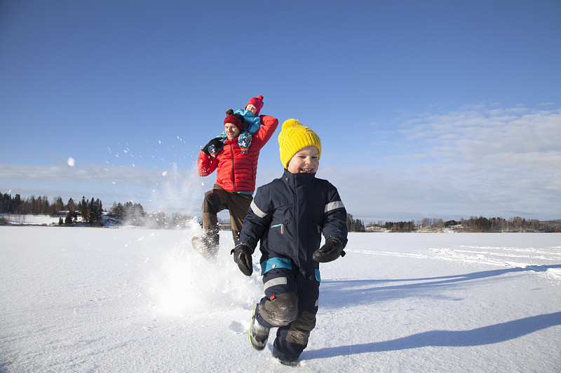 父親和兩個兒子在雪地里玩耍圖片素材