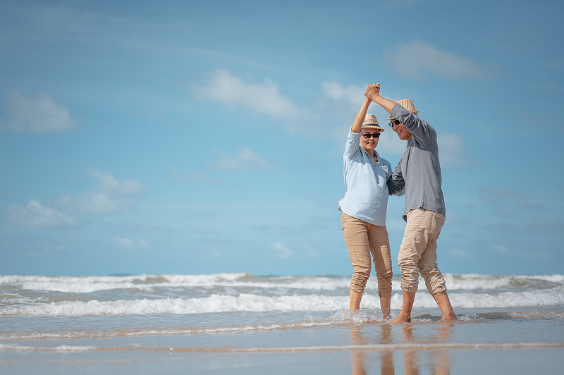 側視圖的夫婦在海灘上對著天空跳舞圖片素材