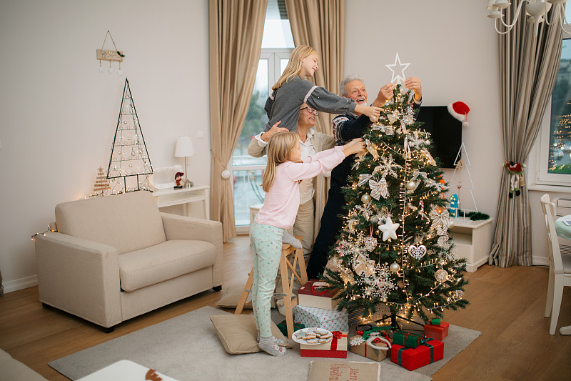 快樂的家庭用裝飾品裝飾圣誕樹圖片素材