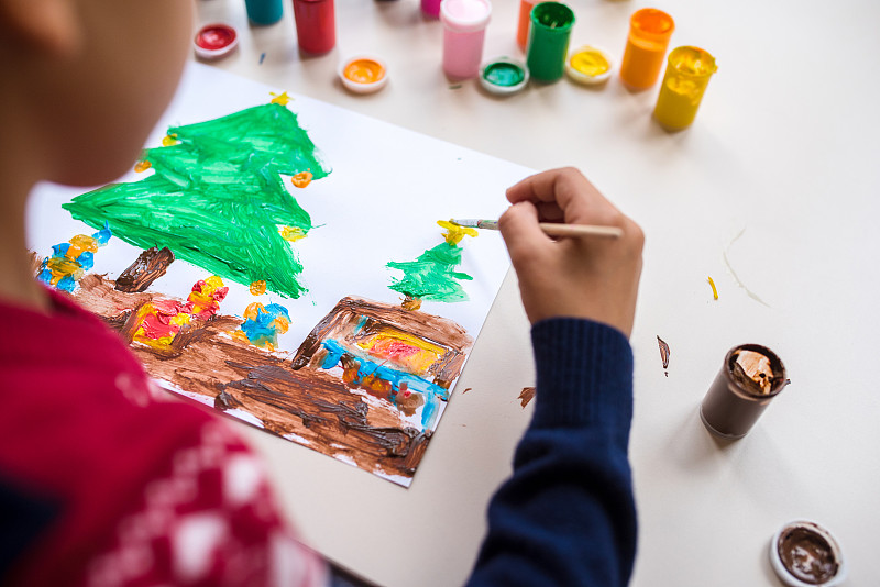 小男孩用彩色顏料在一張白紙上畫了一棵圣誕樹圖片素材