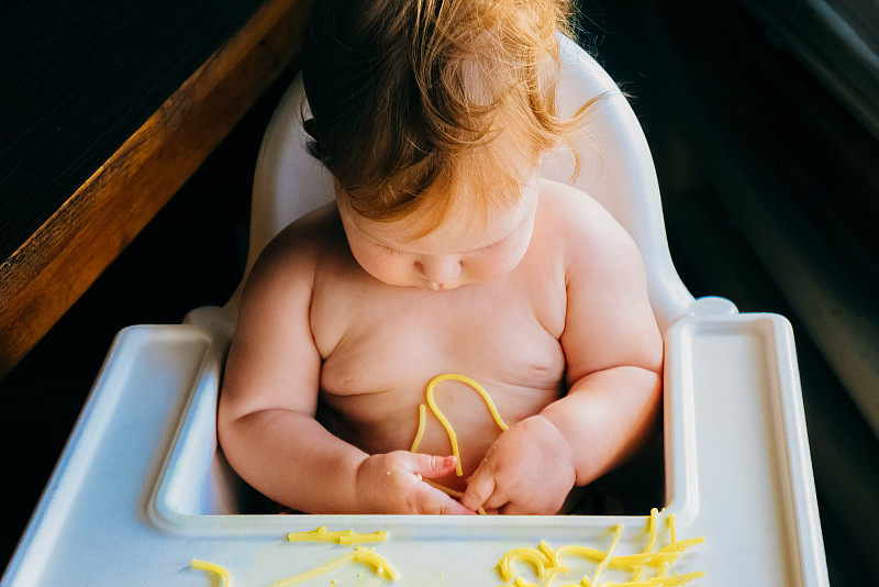 嬰兒吃意大利面。攝影圖片