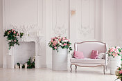 室内灯光工作室的沙发上有粉色的枕头，旁边是装饰着春花、花环、蜡烛的浪漫壁炉图片素材