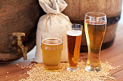 啤酒厂，饮料和酒精概念-接近老啤酒桶，玻璃和袋子与麦芽木桌子图片素材