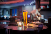在温暖的光线下，在餐厅的木桌上特写一杯啤酒，创造一个轻松的背景图片素材