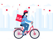 新型冠状病毒肺炎隔离在城里冠状病毒流行。戴着防护面具的外卖女孩骑自行车送餐。免费送货。图片素材