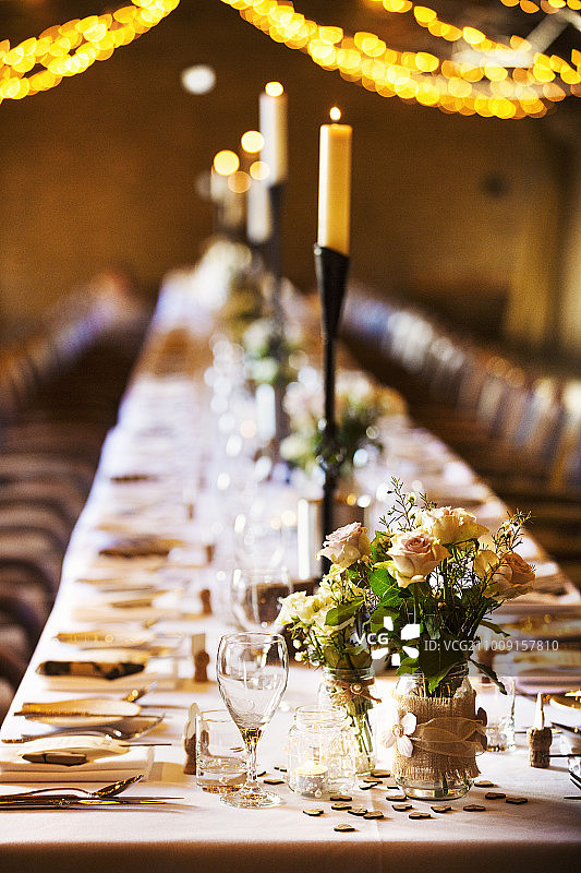 一个为聚会而装饰的婚礼场地，有仙女灯和为晚餐而设置的长桌。图片素材