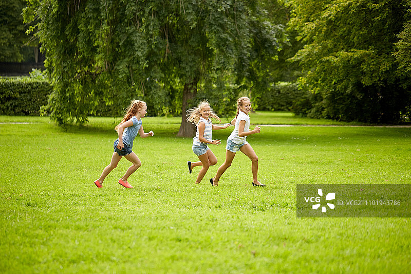友谊，童年，休闲和人的概念-一群快乐的孩子或朋友玩追赶游戏和在夏季公园跑步图片素材