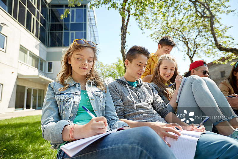 教育，高中和人的概念-快乐青少年组的学生用笔记本在校园学习图片素材