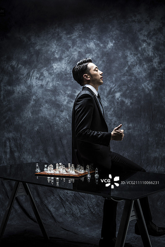 一个人坐在有棋盘的桌子上图片素材