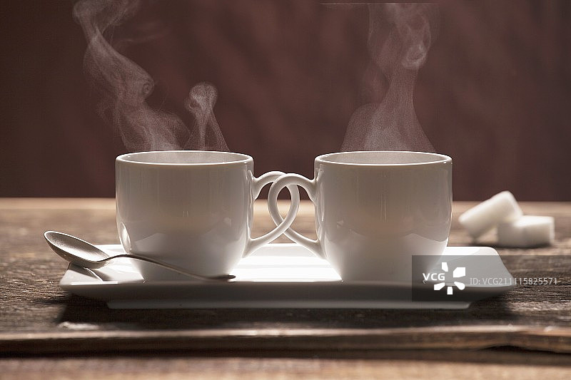 两个热气腾腾的咖啡杯，拉手相连图片素材
