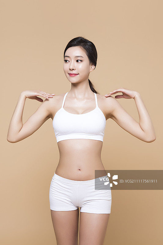 一个年轻女人的肖像穿着白色运动内衣，节食的概念图片素材