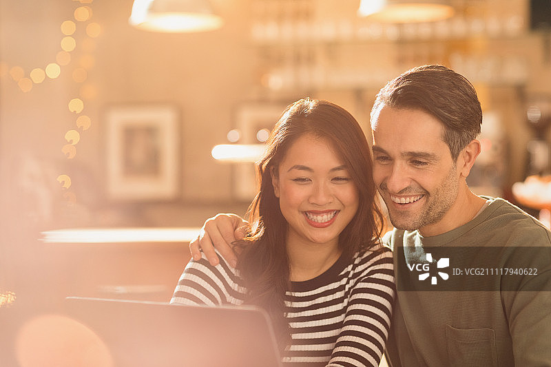 微笑的夫妇在咖啡馆的笔记本电脑视频聊天图片素材