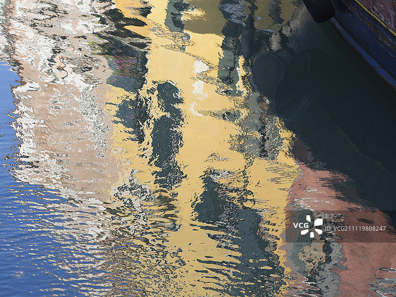 威尼斯。一排粉刷过的房子，映照在运河的水面上。图片素材