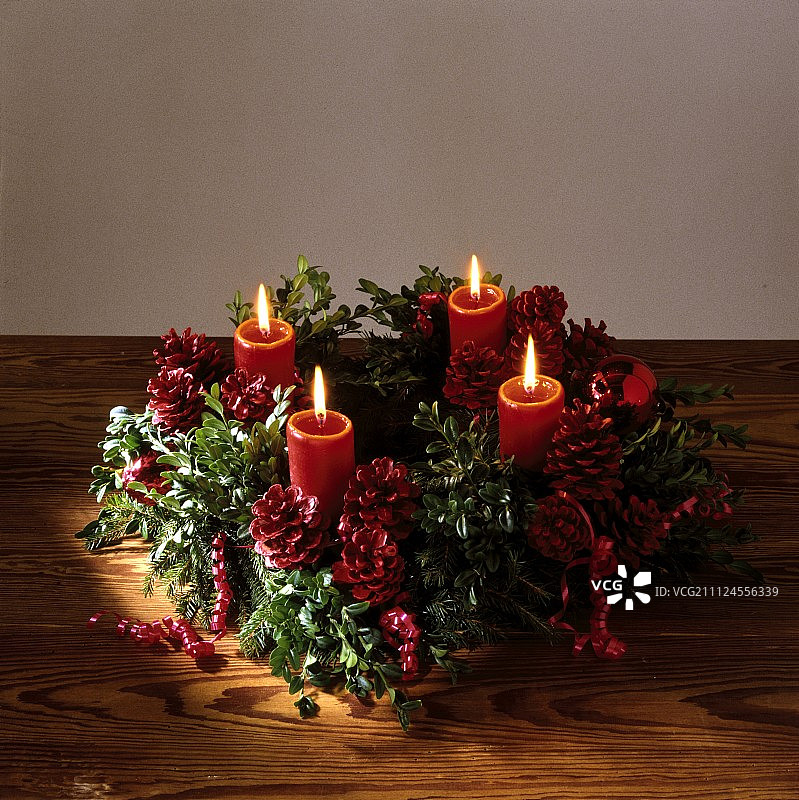 用红色松果和点燃的蜡烛装饰的圣诞花环图片素材