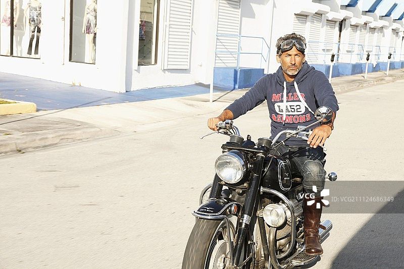 一个穿着连帽运动衫的男人坐在摩托车上图片素材