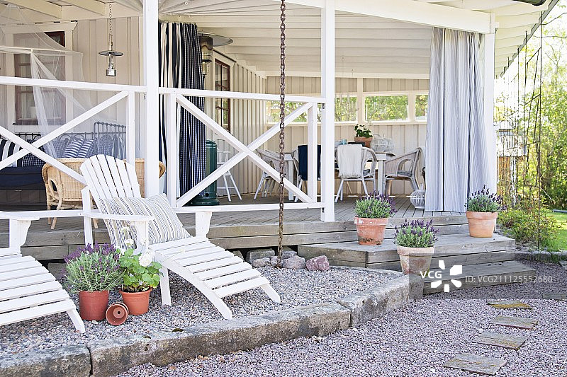 白色的木制躺椅在木屋阳台前的砾石露台上图片素材