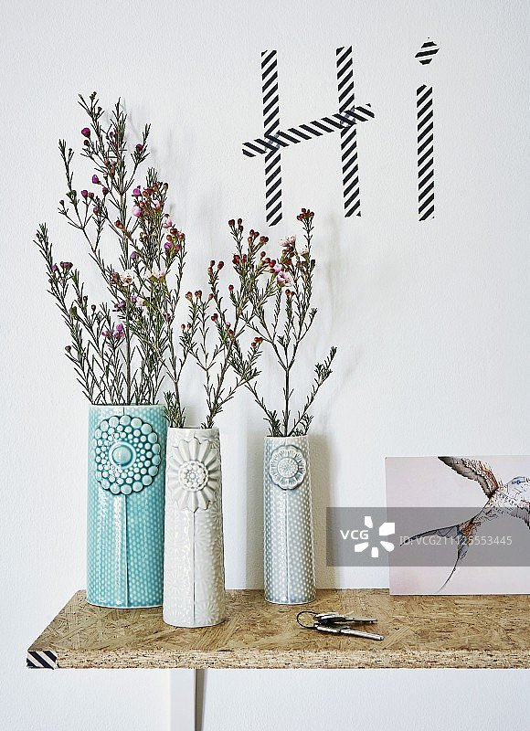 丹麦设计师的花瓶放在DIY的刨花板架上，下面是用washi胶带写在墙上的问候图片素材
