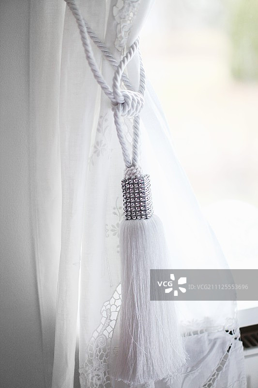经典的白色绳结，在窗帘上有流苏图片素材