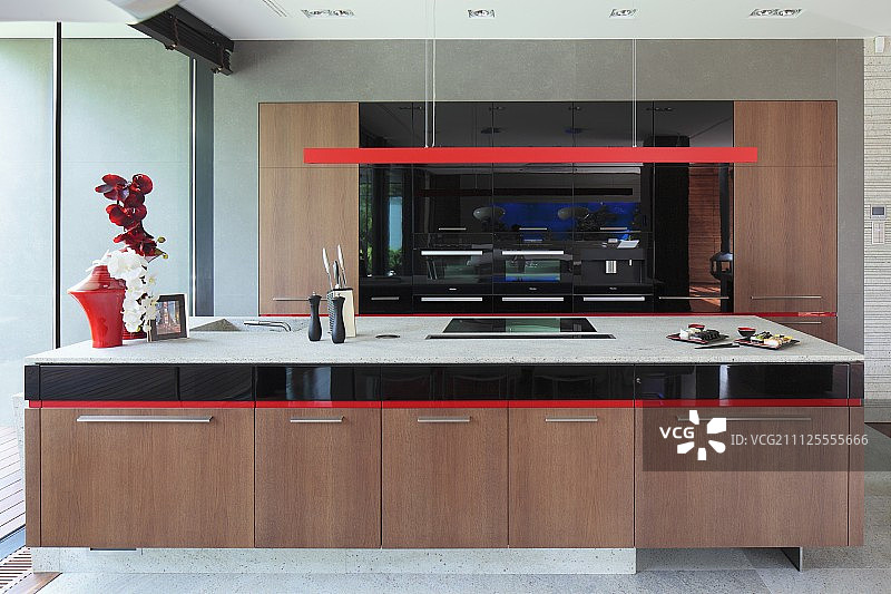 带有木质底柜的长厨房柜台，一盏带有条形外壳的红色吊灯，位于现代开放式厨房中图片素材
