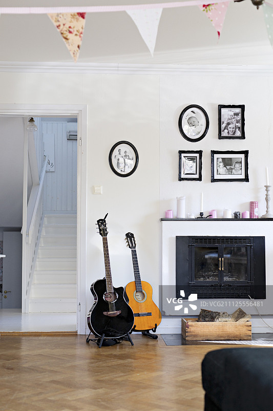 在乡村风格的客厅里，打开的壁炉旁边放着吉他，下面是相框中的家庭照片图片素材