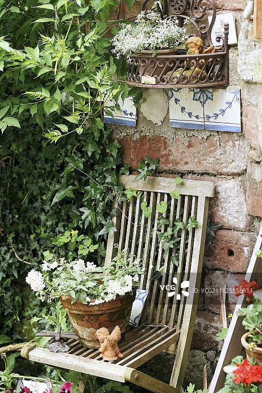 开花植物在赤陶罐上的木制花园椅子图片素材