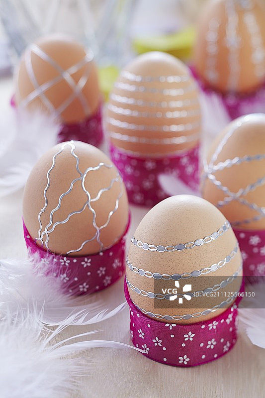 用银条装饰的棕色鸡蛋放在手工制作的蛋杯里图片素材