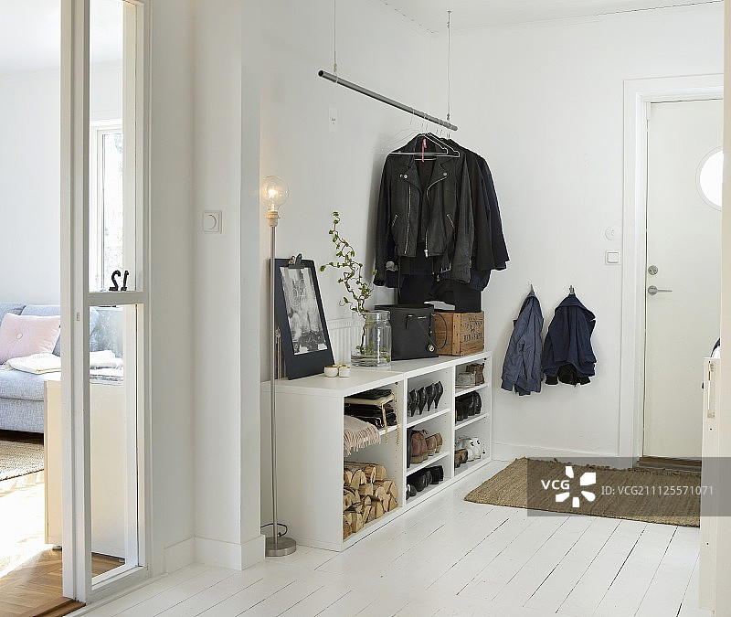 白色走廊与开放式前鞋架，悬挂大衣轨和标准灯在斯堪的纳维亚室内图片素材