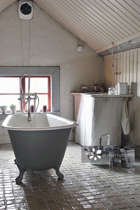 独立的，复古浴缸上的玻璃，瓷砖地板在阁楼浴室，山墙窗户图片素材