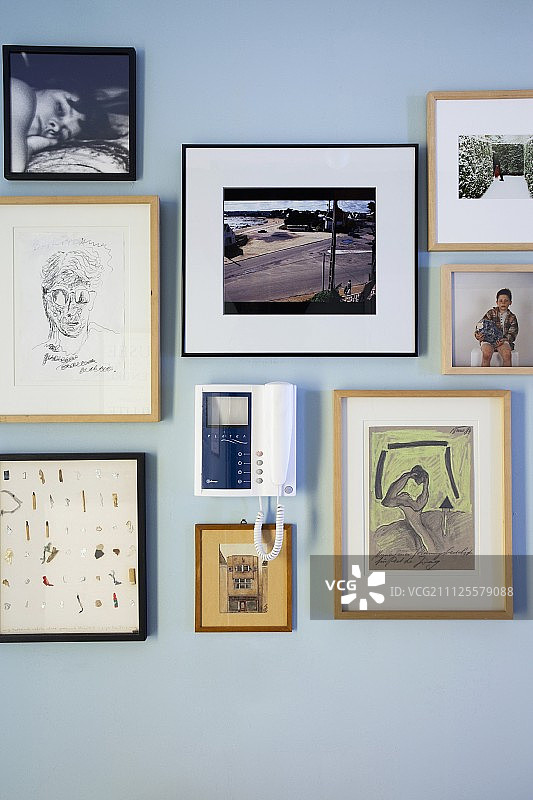 对讲机周围的画框和照片的收藏在墙上漆成淡蓝色图片素材