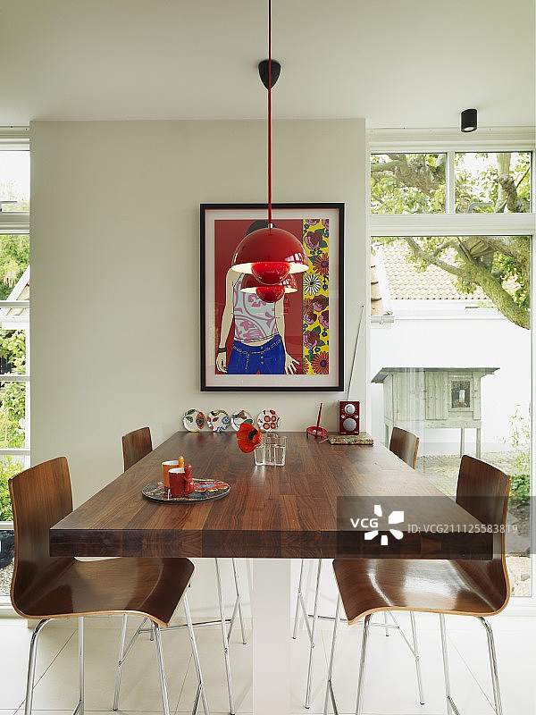 高的胡桃木桌子和酒吧凳，红色吊灯下的木制贝壳座椅和落地窗之间图片素材
