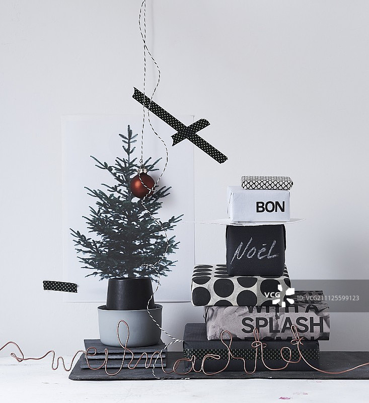 一堆用黑白纸包裹的礼物，旁边印着圣诞树的图片图片素材