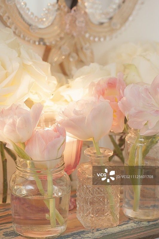 精致的郁金香在花瓶和罐子在架子上和浪漫的镜子装饰女性的浴室图片素材