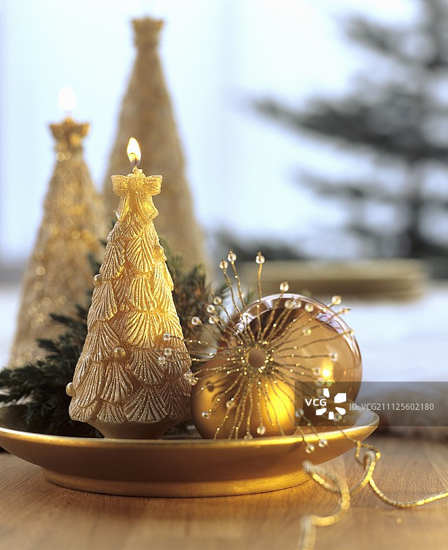 用金制的盘子装上金色的装饰物和圣诞树形状的蜡烛图片素材