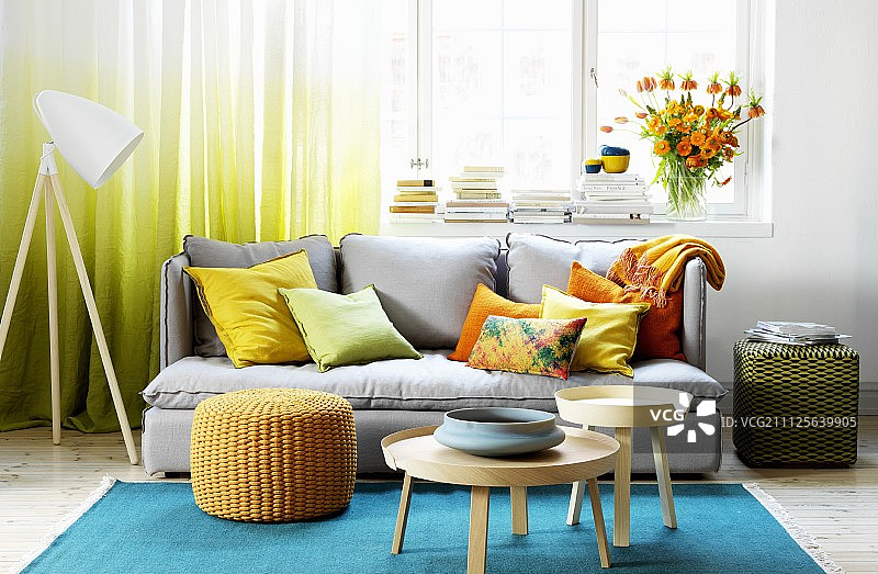 色彩丰富的客厅，绿松石地毯，灰色沙发和黄色和橙色的散垫图片素材
