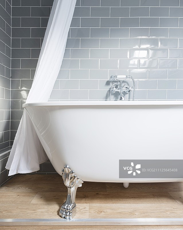 脚爪贴在灰色瓷砖上的独立式浴缸图片素材
