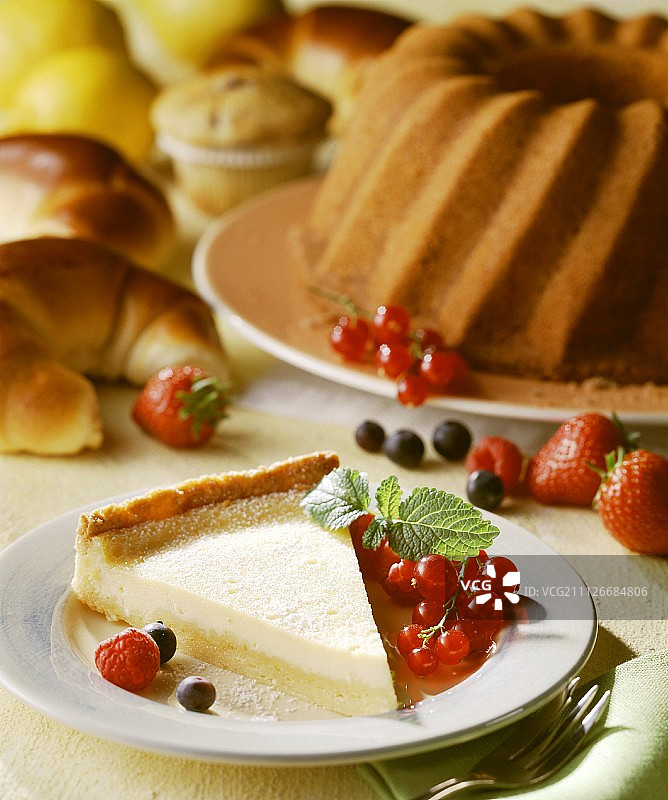 在水果蛋糕，羊角面包，松饼前面放一块芝士蛋糕图片素材