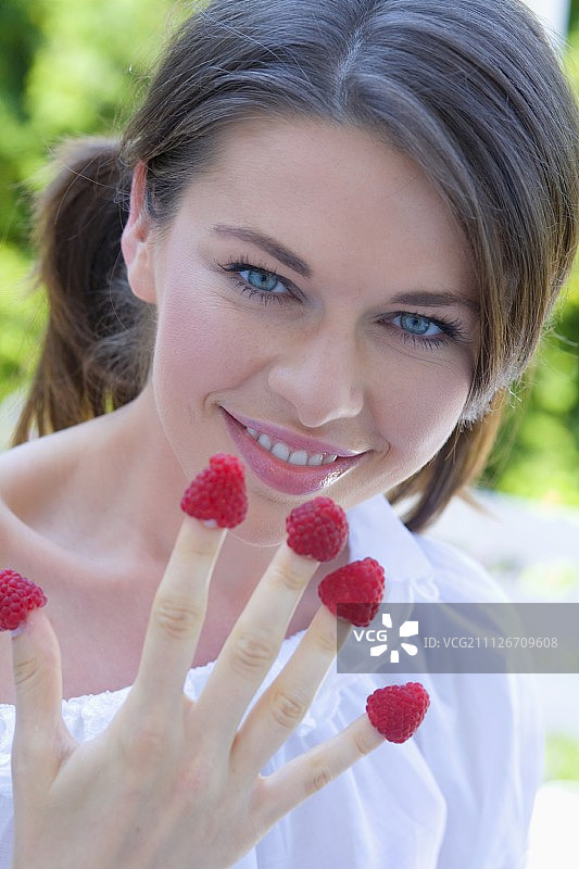 手指上有树莓的年轻女子图片素材