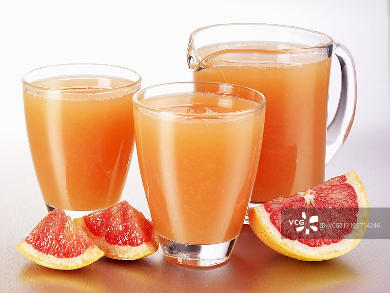 用玻璃杯和一个玻璃壶装的粉色葡萄柚汁图片素材