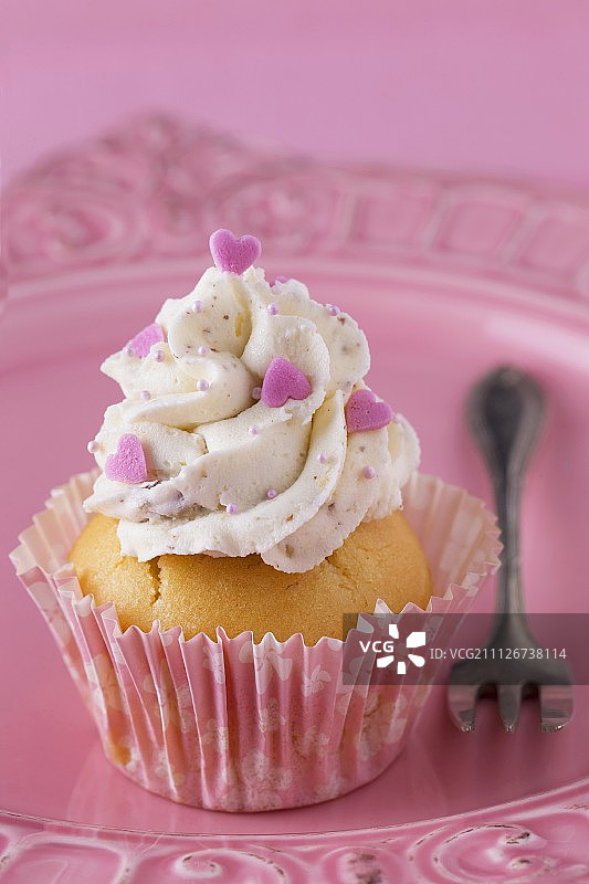 用奶油和粉色心形装饰的纸杯蛋糕图片素材