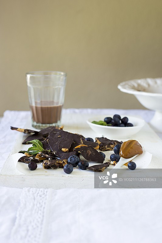 碎黑巧克力加盐焦糖，新鲜蓝莓和一杯巧克力牛奶图片素材
