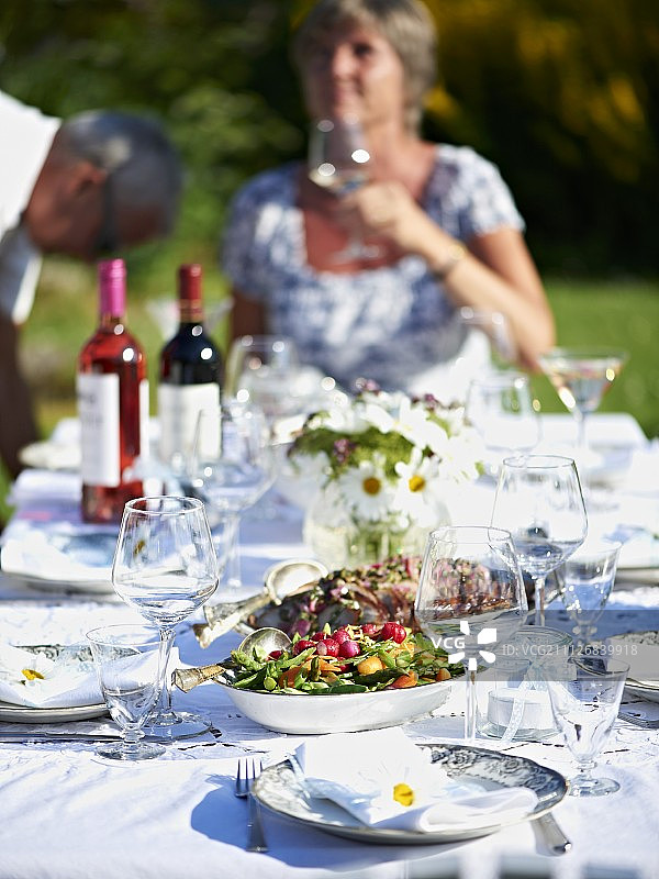 一桌为夏季聚会准备的烤猪肉、沙拉和葡萄酒图片素材