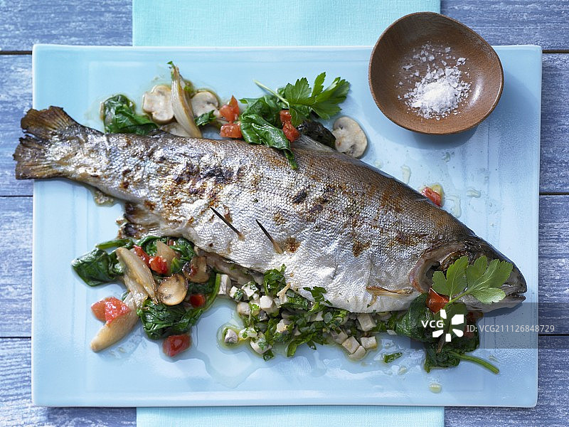 填饱了的鲑鱼鳟鱼配上菠菜叶图片素材
