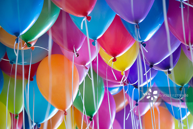 节日里，五颜六色的气球用氦气绑在白色的丝带上图片素材