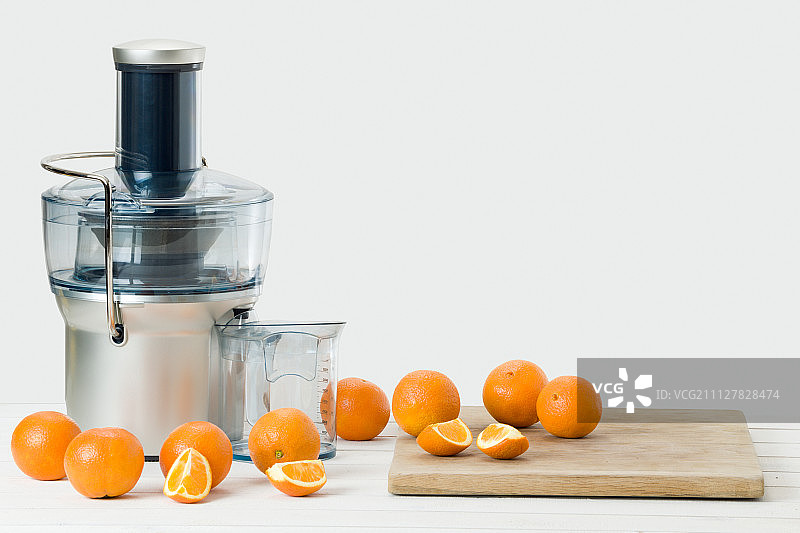 现代的电动榨汁机和新鲜的橙子，白色的背景和复制空间图片素材