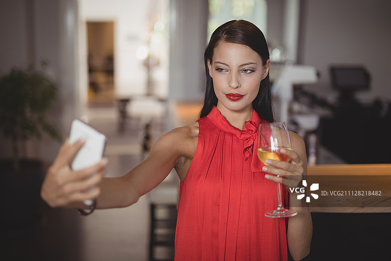 一名女子在餐厅喝酒时用手机自拍图片素材